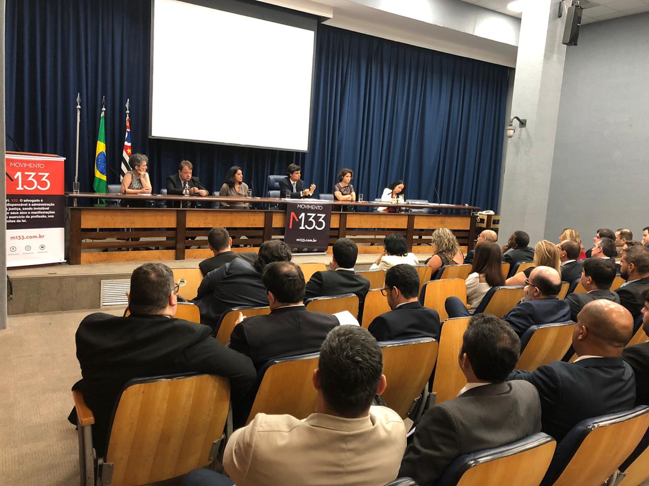 Um grupo de pessoas está sentado em uma sala de aula assistindo a uma apresentação.