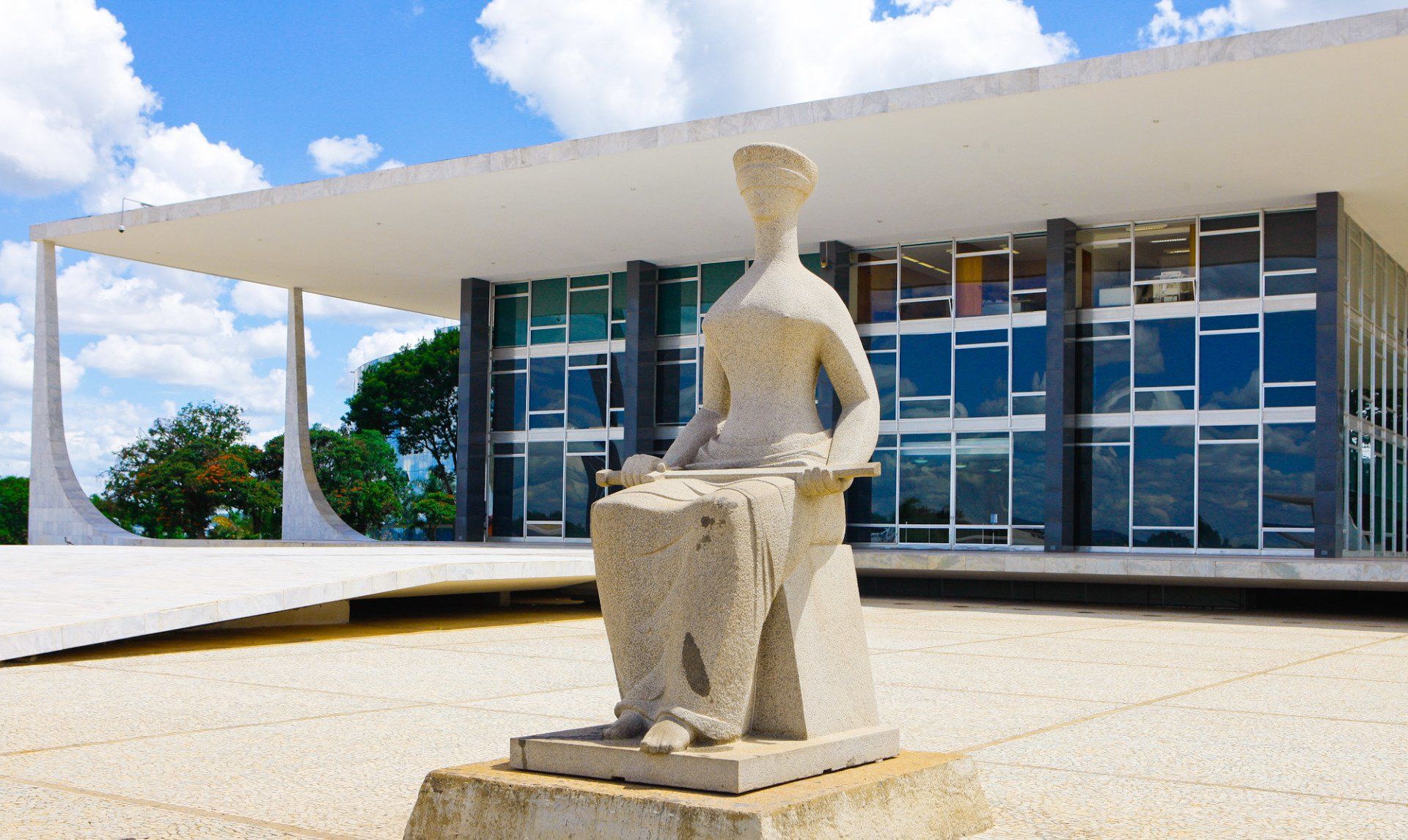 Uma estátua de uma mulher sentada em frente a um prédio.