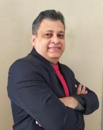 Um homem de terno e gravata está de pé com os braços cruzados.