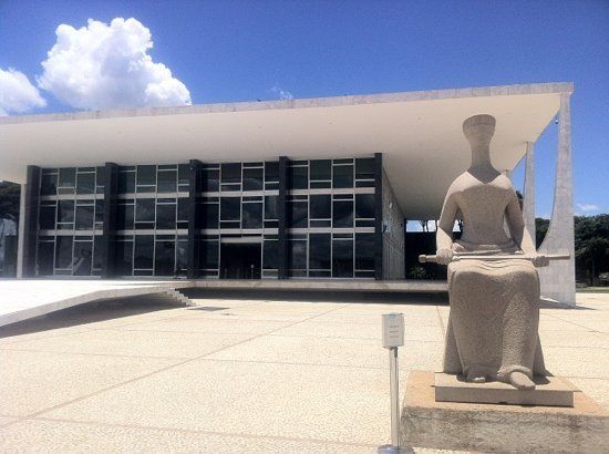Uma estátua de uma mulher sentada em frente a um prédio