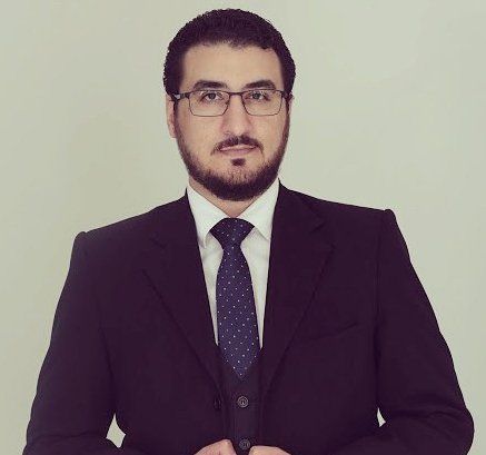 Um homem com barba vestindo terno e gravata