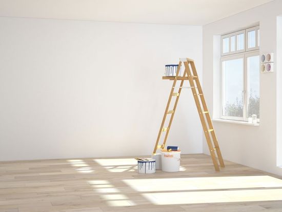 una stanza imbiancata , una scala in legno e dei secchi di pittura