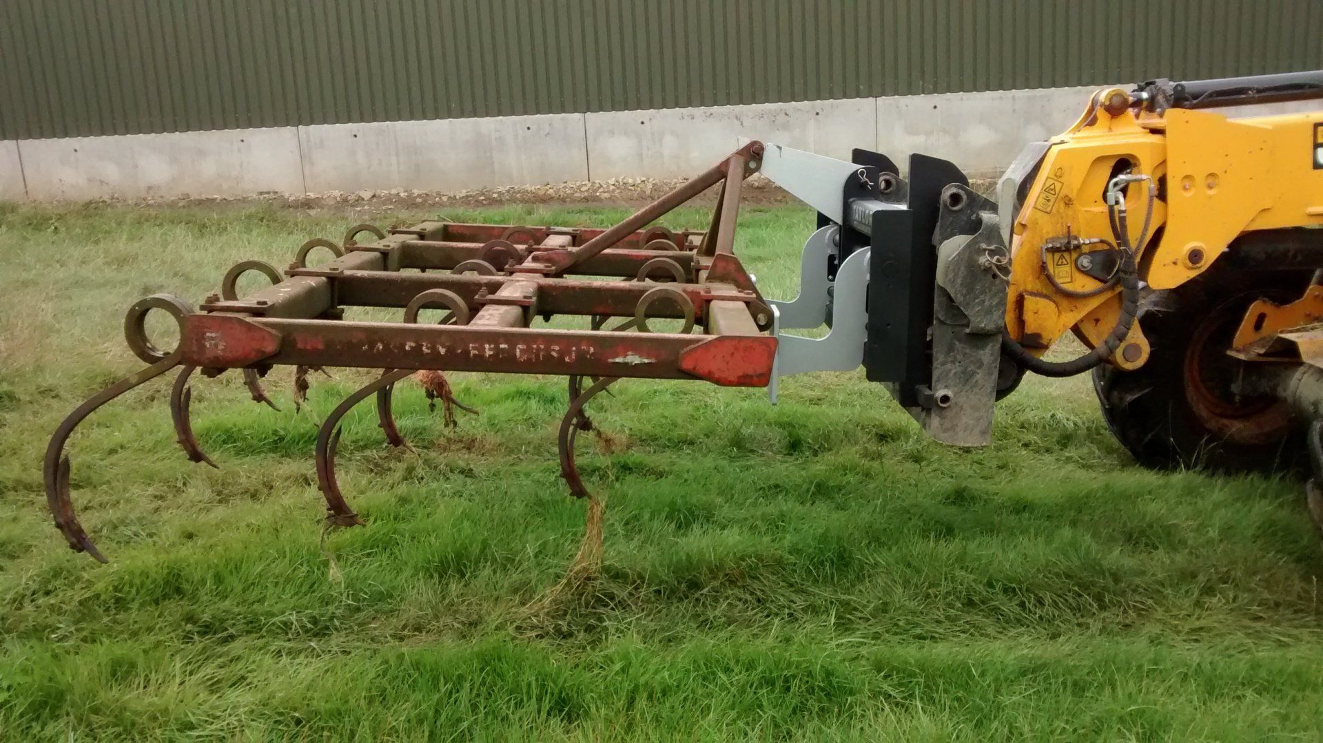 Hooklifter Attachment on a JCB telehandler lifting a harrow