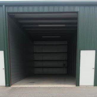 Green storage unit, open door reveals interior, two white doors on sides.