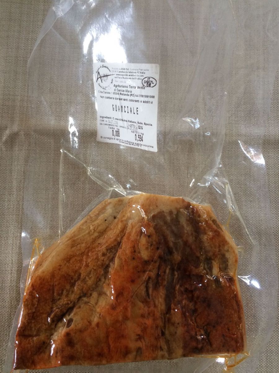 Sacchetto di plastica trasparente con un alimento di colore marrone rossastro e una piccola etichetta su sfondo neutro.