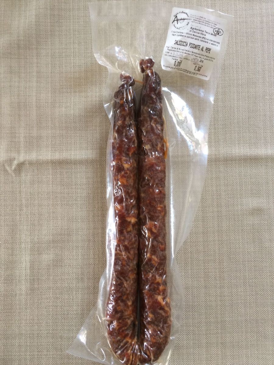 Due salsicce stagionate sottovuoto su una superficie chiara con un'etichetta del prodotto allegata