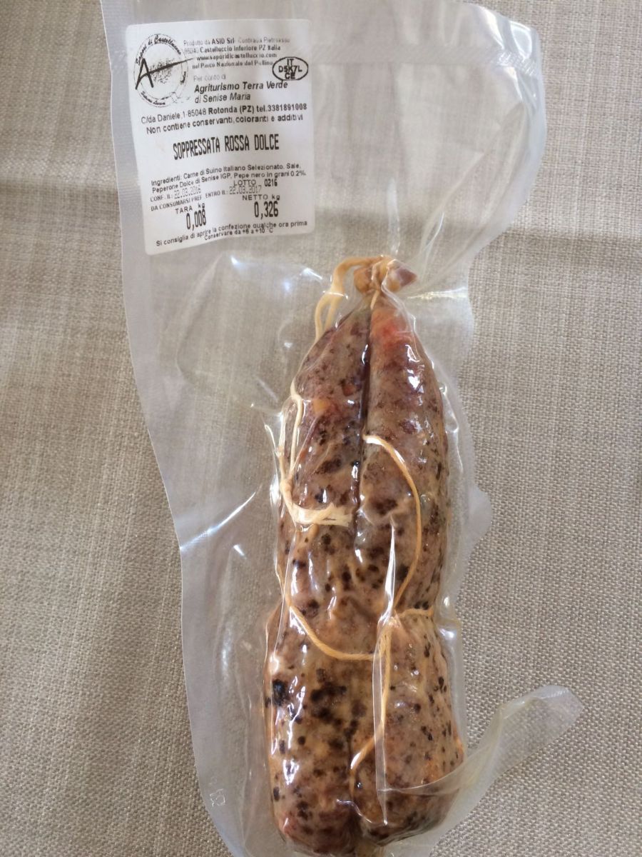 Barretta di granola al cioccolato confezionata in un involucro di plastica trasparente su una superficie di tessuto leggero.