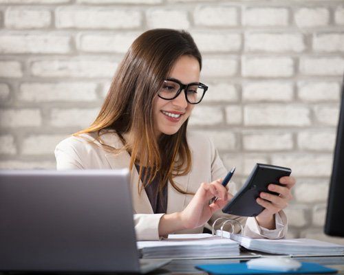Individual Accountant — Smiling Accountant Using Calculator in Petersburg, VA Business woman using a calculator
