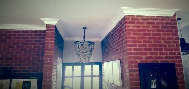 A hallway with a brick wall and a chandelier hanging from the ceiling.