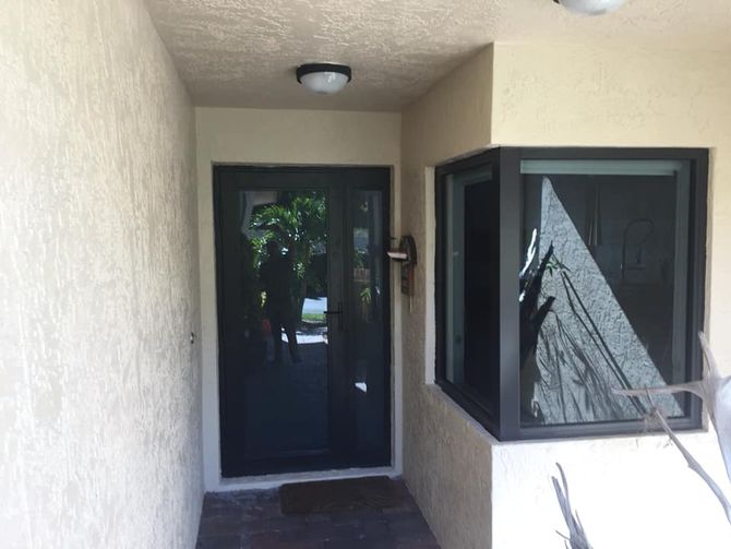 Entryway with dark door, window, and off-white stucco walls. Highland Beach FL