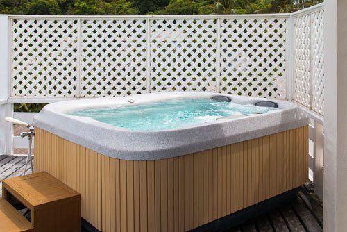 Hot tub on a wooden deck, with a lattice backdrop. The tub is filled with water.