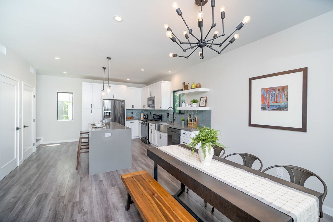 The full kitchen and dining area inside an accessory dwelling unit (ADU) backyard home, featuring plenty of space, an island, and modern all-electric appliances. 