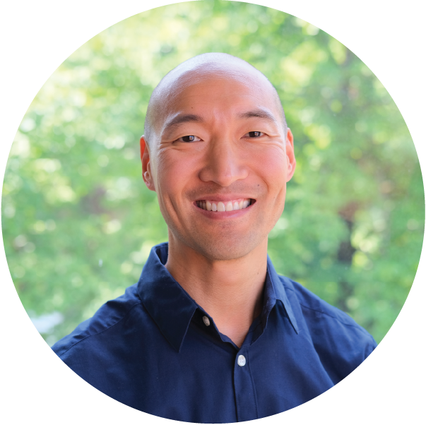 A bald man in a blue shirt is smiling in a circle.