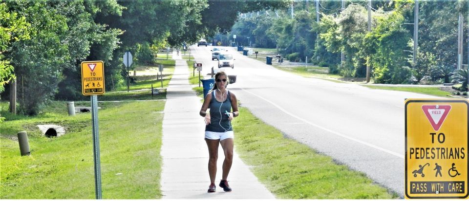 A walker on the sidewalk on Canal Road in Orange Beach, Alabama.