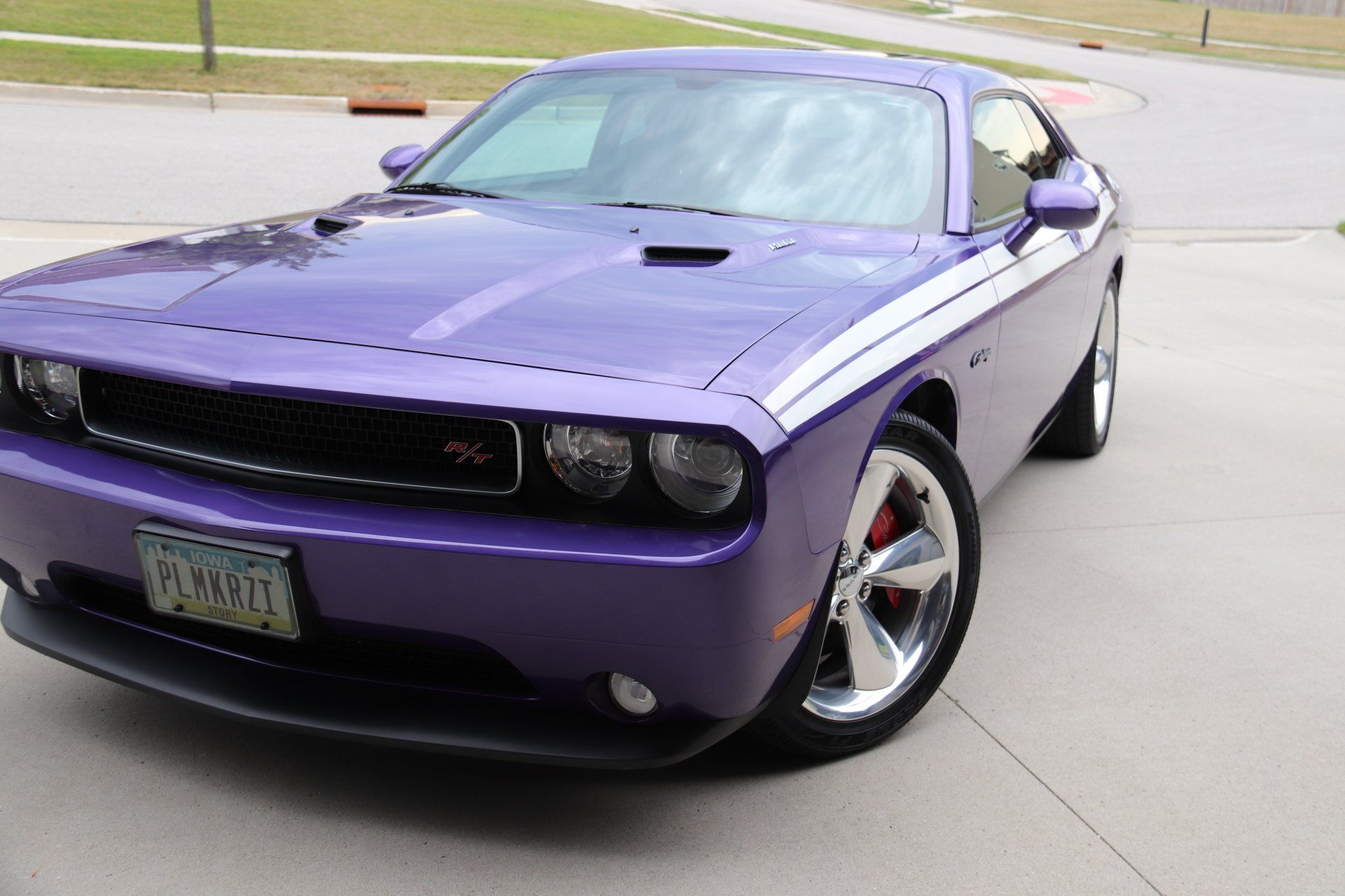 A purple dodge challenger is parked in a driveway
