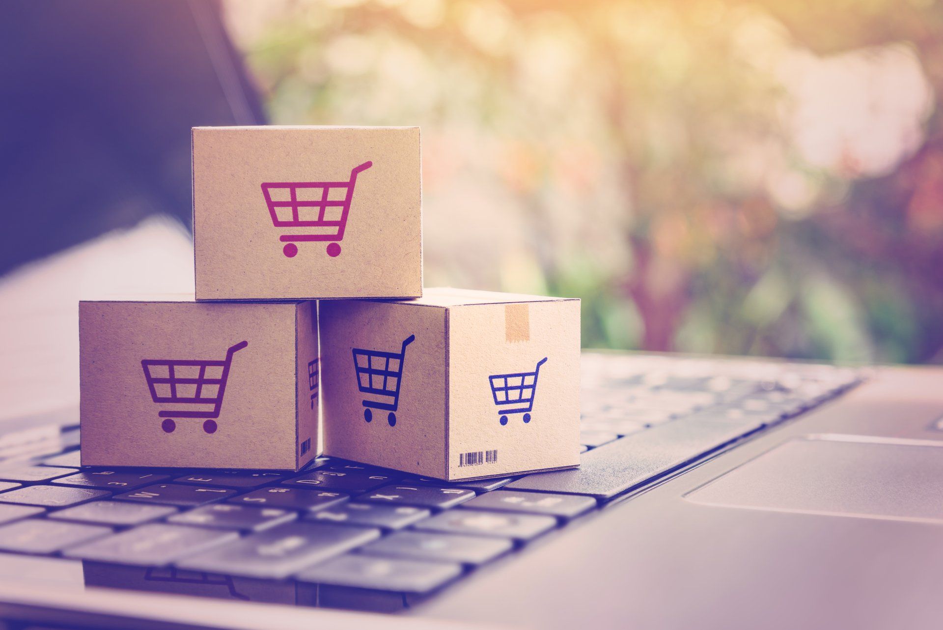 Three cardboard boxes with shopping carts on them are stacked on top of each other on a laptop keyboard.