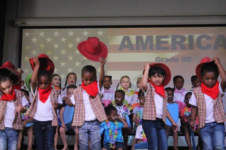 A group of children are dancing in front of a screen that says america