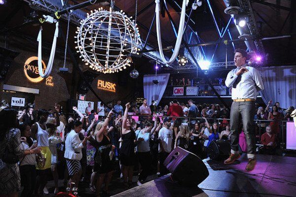 Limousine Rental Seattle A man is singing into a microphone in front of a crowd at a club called rusk
