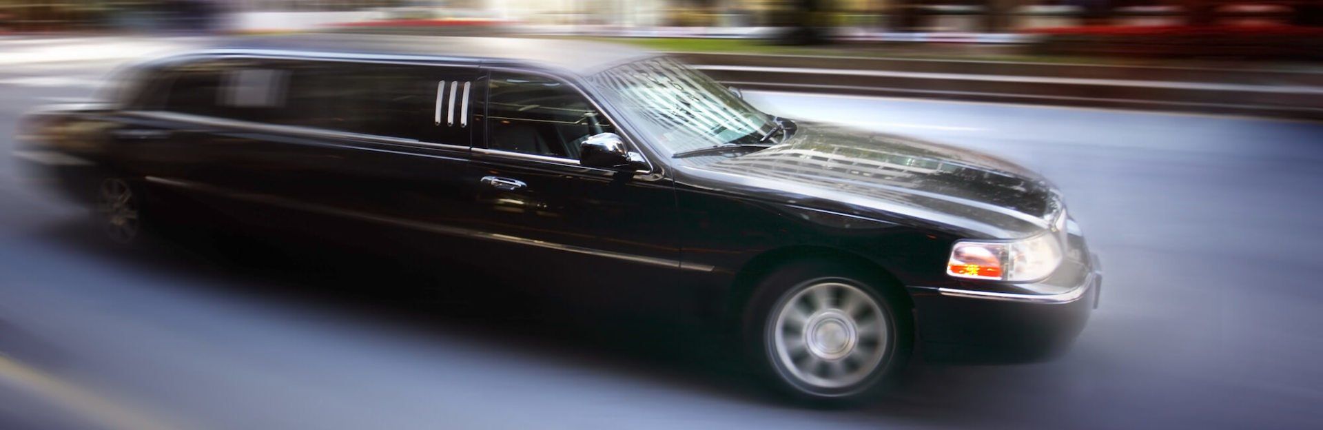 A black limousine is driving down a city street.