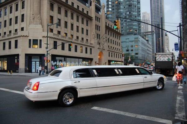 Best Corporate Car Service Near Me A white limousine is driving down a city street
