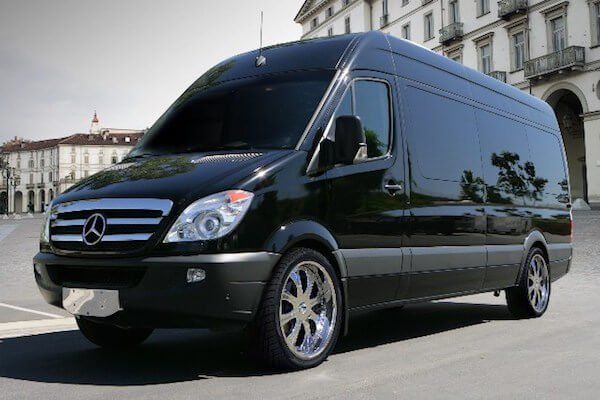Group Transporation A black mercedes van is parked in front of a building