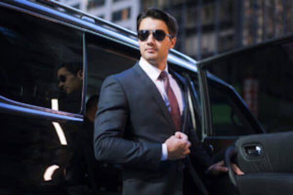 A man in a suit and tie is getting out of a car.