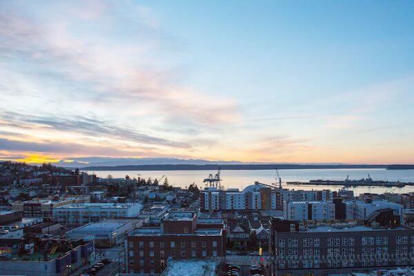 An aerial view of a city at sunset with a body of water in the background.