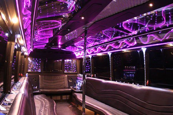 The inside of a limousine with purple lights on the ceiling.