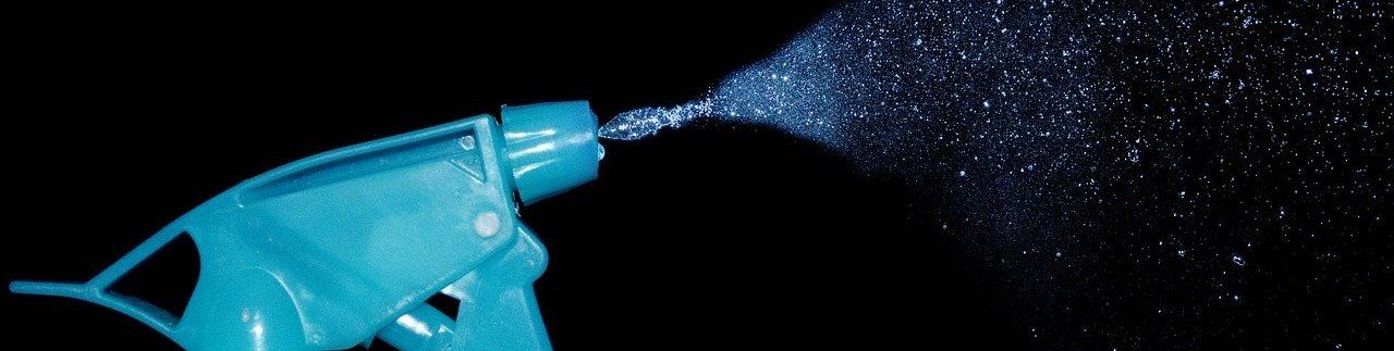 A blue spray bottle is spraying water on a black background.