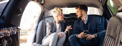A man and a woman are sitting in the back seat of a car.