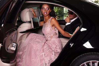 prom limo rental and transportation services A woman in a pink dress is sitting in the back seat of a car.