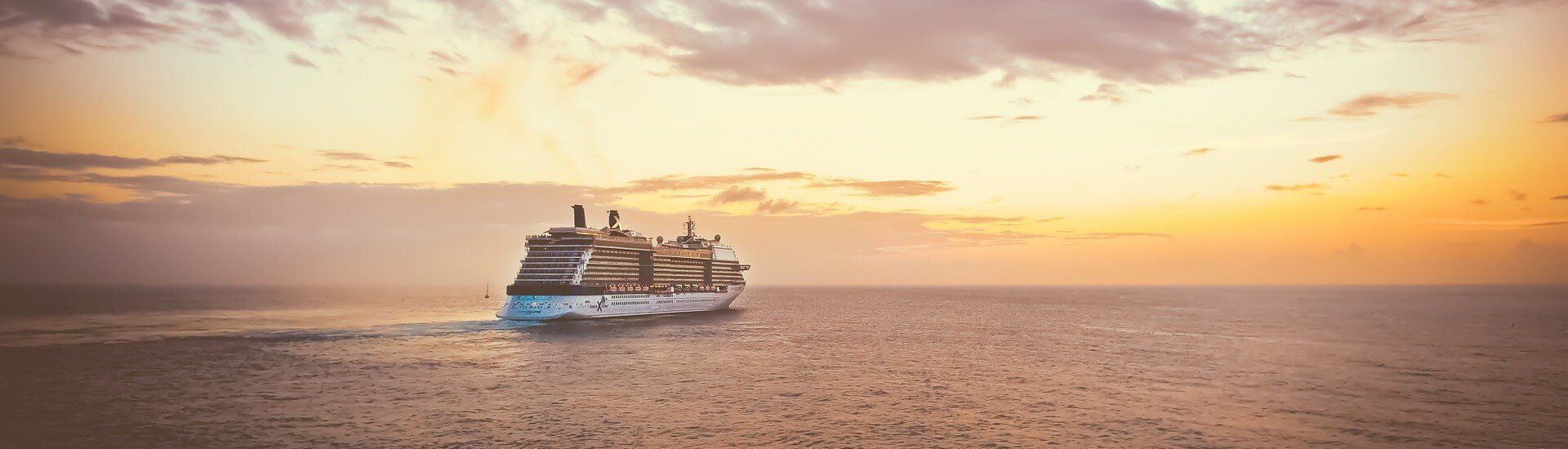 A cruise ship is floating on top of a large body of water at sunset.