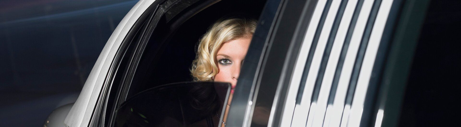 A woman is peeking out of the window of a limousine.