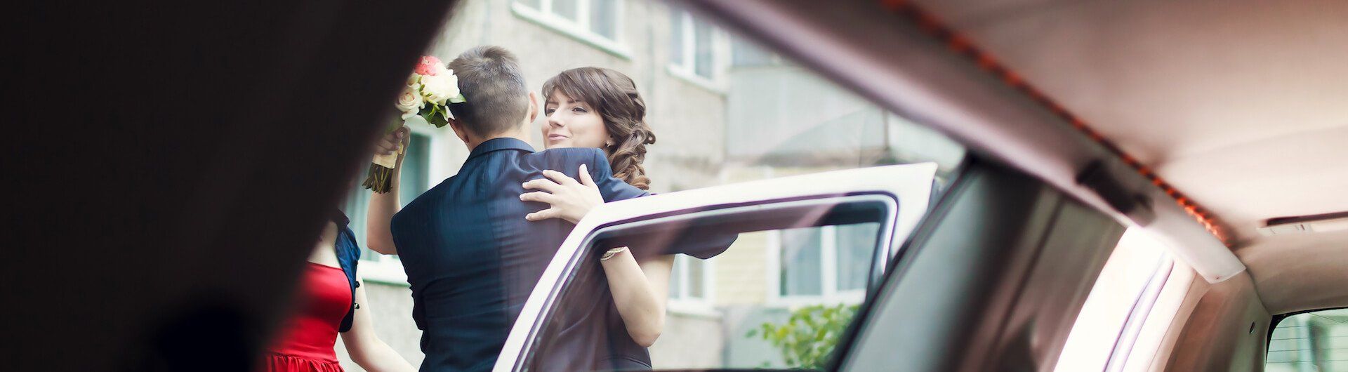 A bride and groom are getting out of a car.