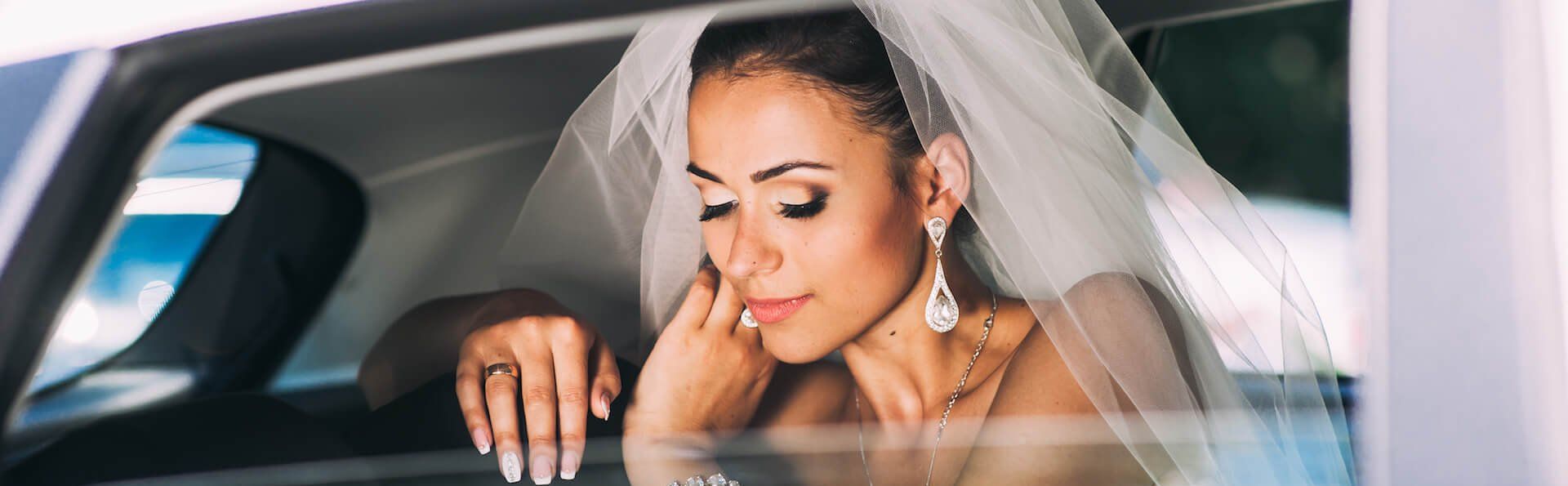 best Seattle limo services A bride in a veil is sitting in the back seat of a car.