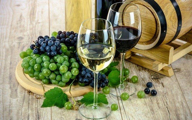 A bunch of grapes and two glasses of wine on a wooden table.