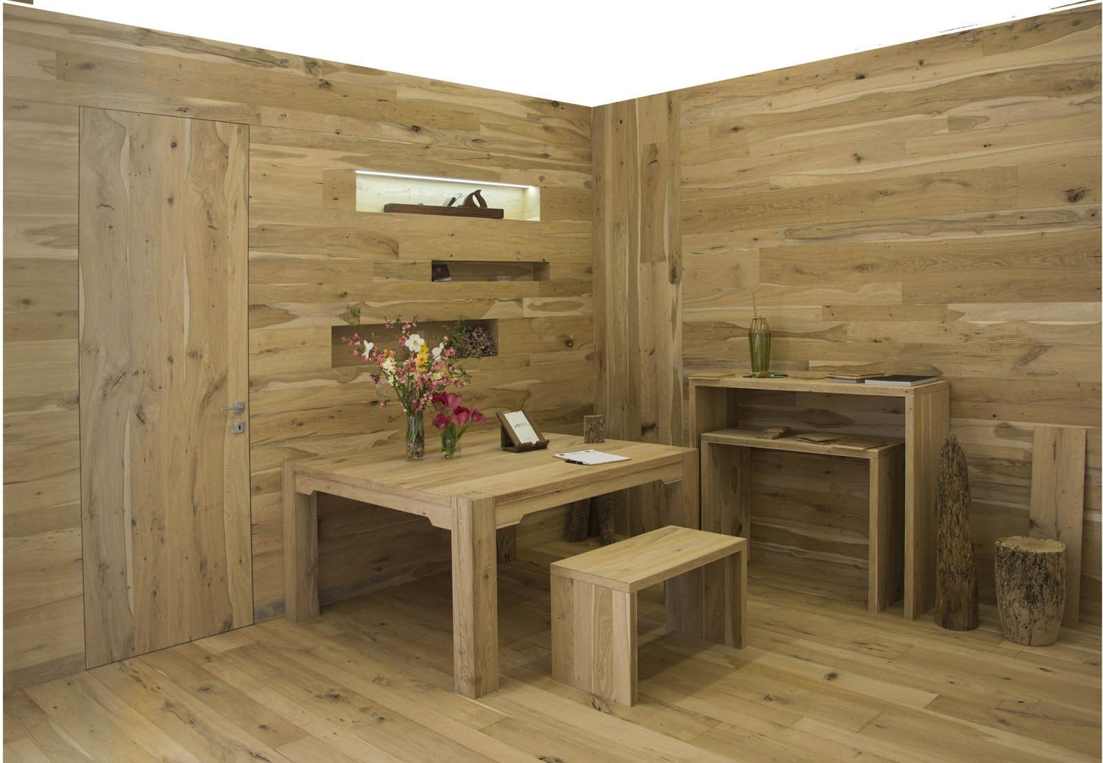 Una stanza moderna con pareti rivestite in legno chiaro, un tavolo da pranzo abbinato con panca e mensole a muro incassate.