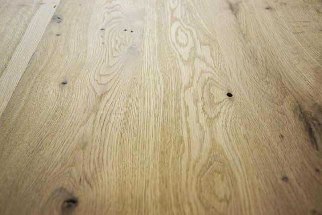 Primo piano di un pavimento in legno di rovere chiaro con venature e nodi naturali ben visibili.