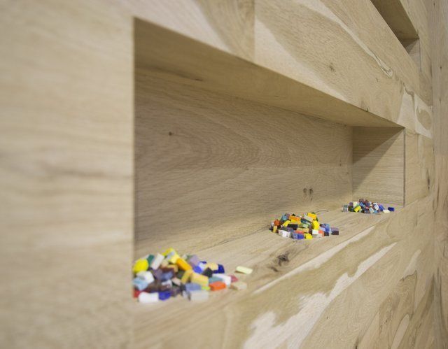 Due piccoli mucchietti di frammenti di vetro colorati sono sistemati all'interno di una mensola di legno incassata.