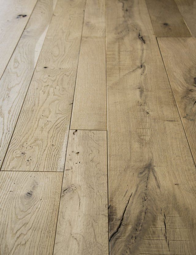 Primo piano di un pavimento in legno massello di tonalità chiara, con venature, nodi e texture naturali ben visibili.