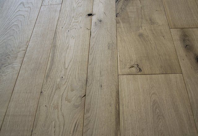 Assi di legno chiaro per pavimenti, con venature naturali, nodi e sottili variazioni di colore.