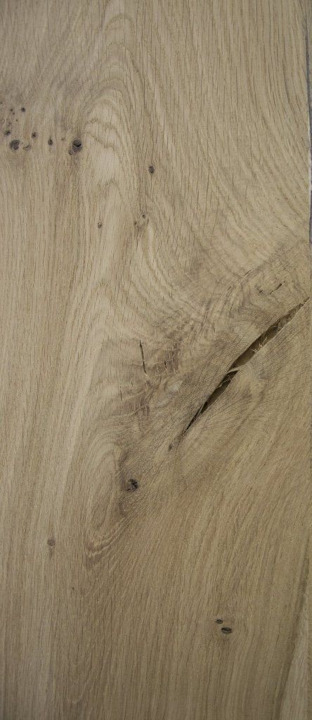 Primo piano di un pavimento in legno di rovere chiaro con una vistosa crepa diagonale scura e diversi nodi naturali del legno.