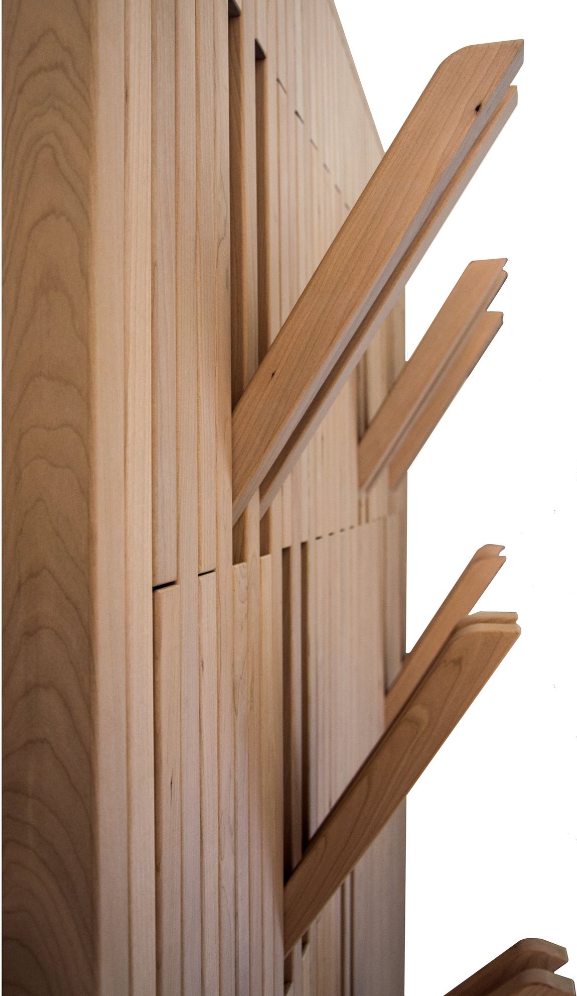 Un appendiabiti a parete realizzato con listelli di legno verticali, alcuni dei quali inclinati verso l'esterno per fungere da ganci.