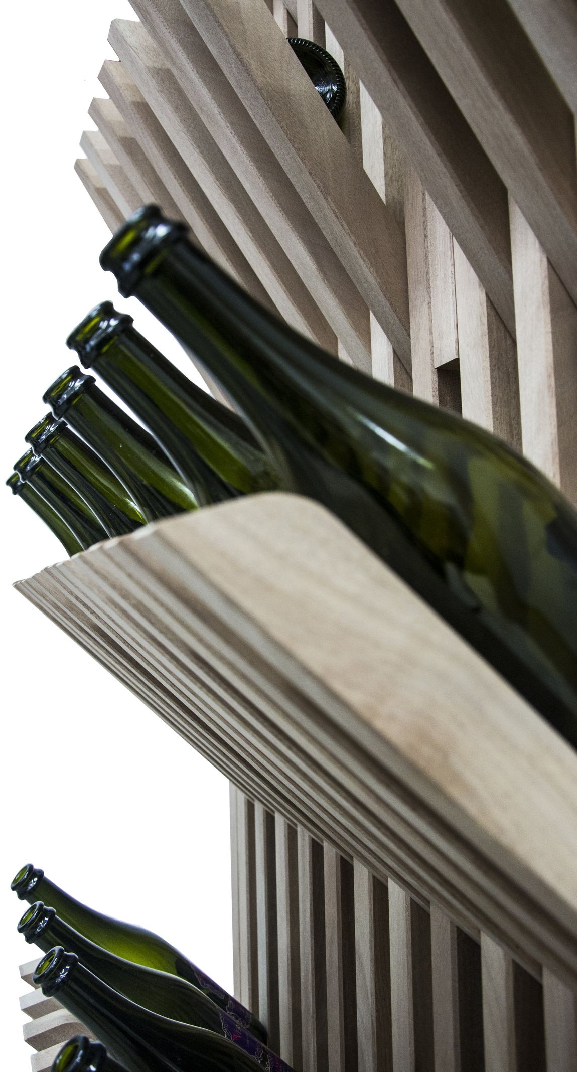 Un portabottiglie minimalista realizzato con listelli di cartone impilati che sorreggono diverse bottiglie di vetro verde disposte in diagonale.