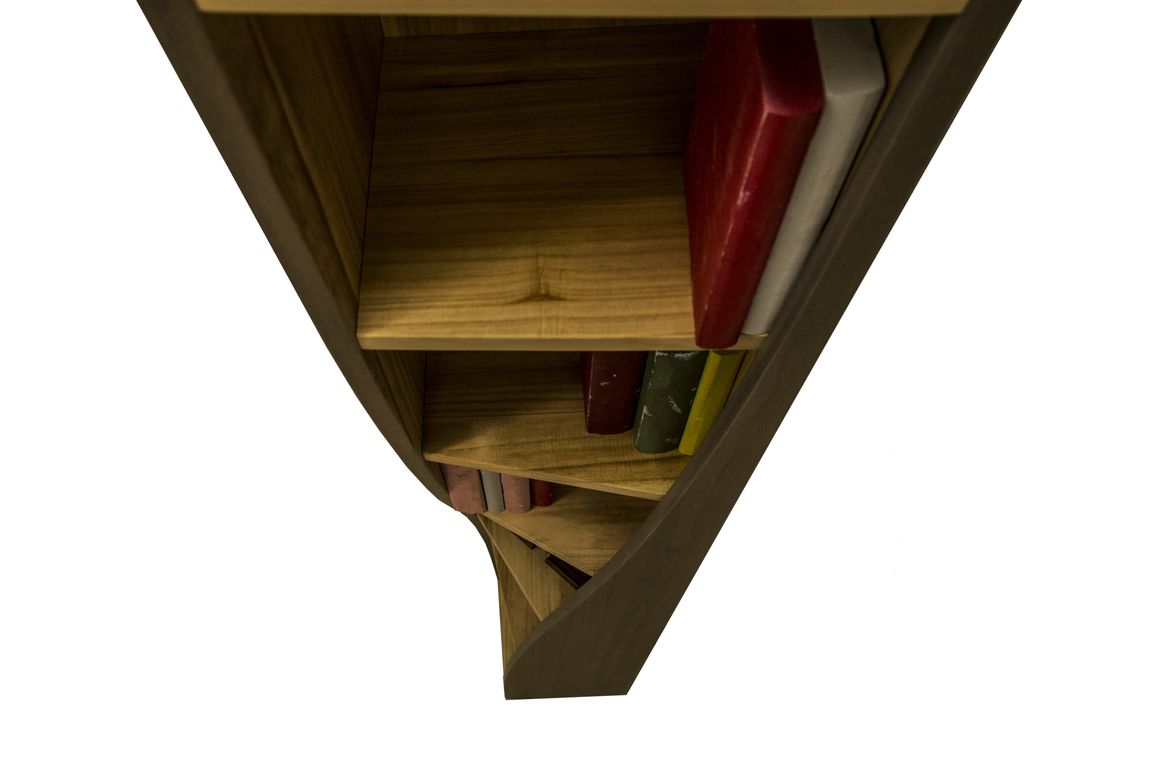 Una libreria in legno alta e a spirale, con alcuni libri sugli scaffali superiori, ripresa da una prospettiva verticale e dall'alto.