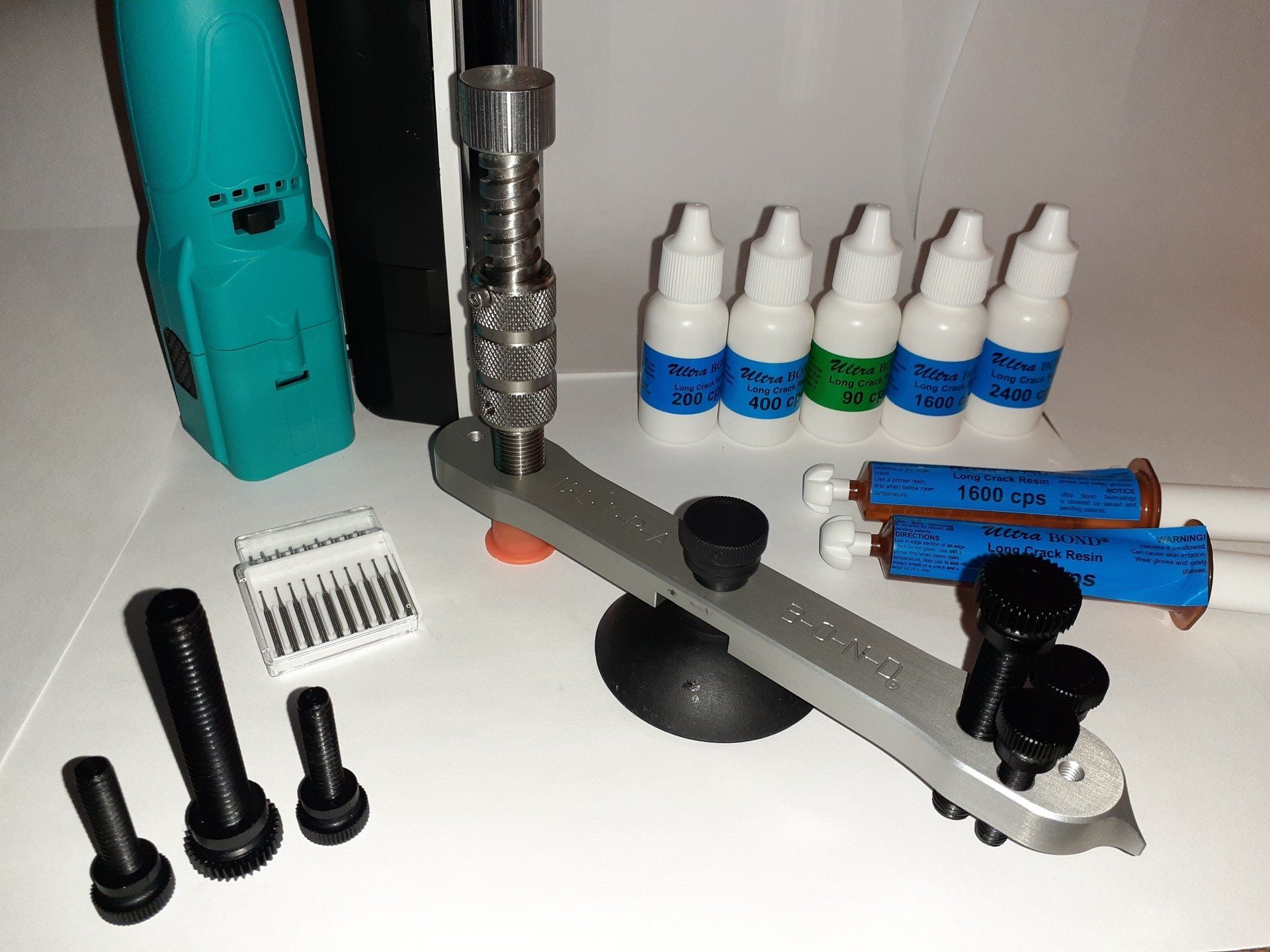 A bunch of windshield repair tools and resin bottles on a table