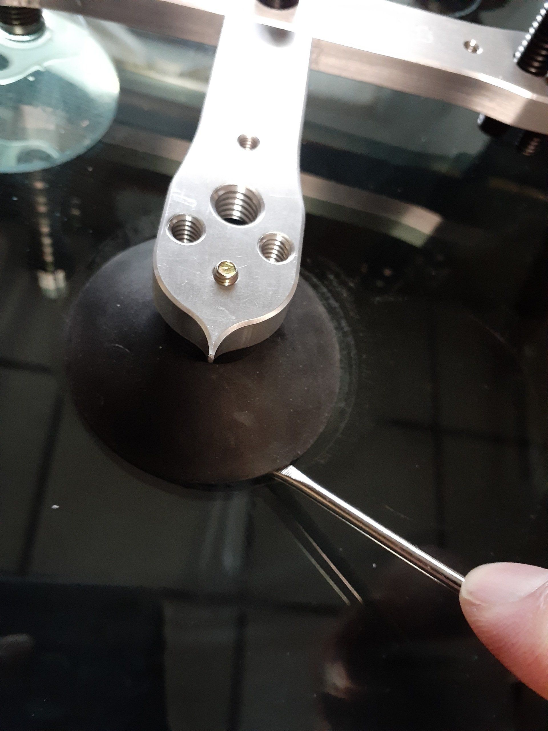 A person is holding a pair of tweezers over a piece of metal