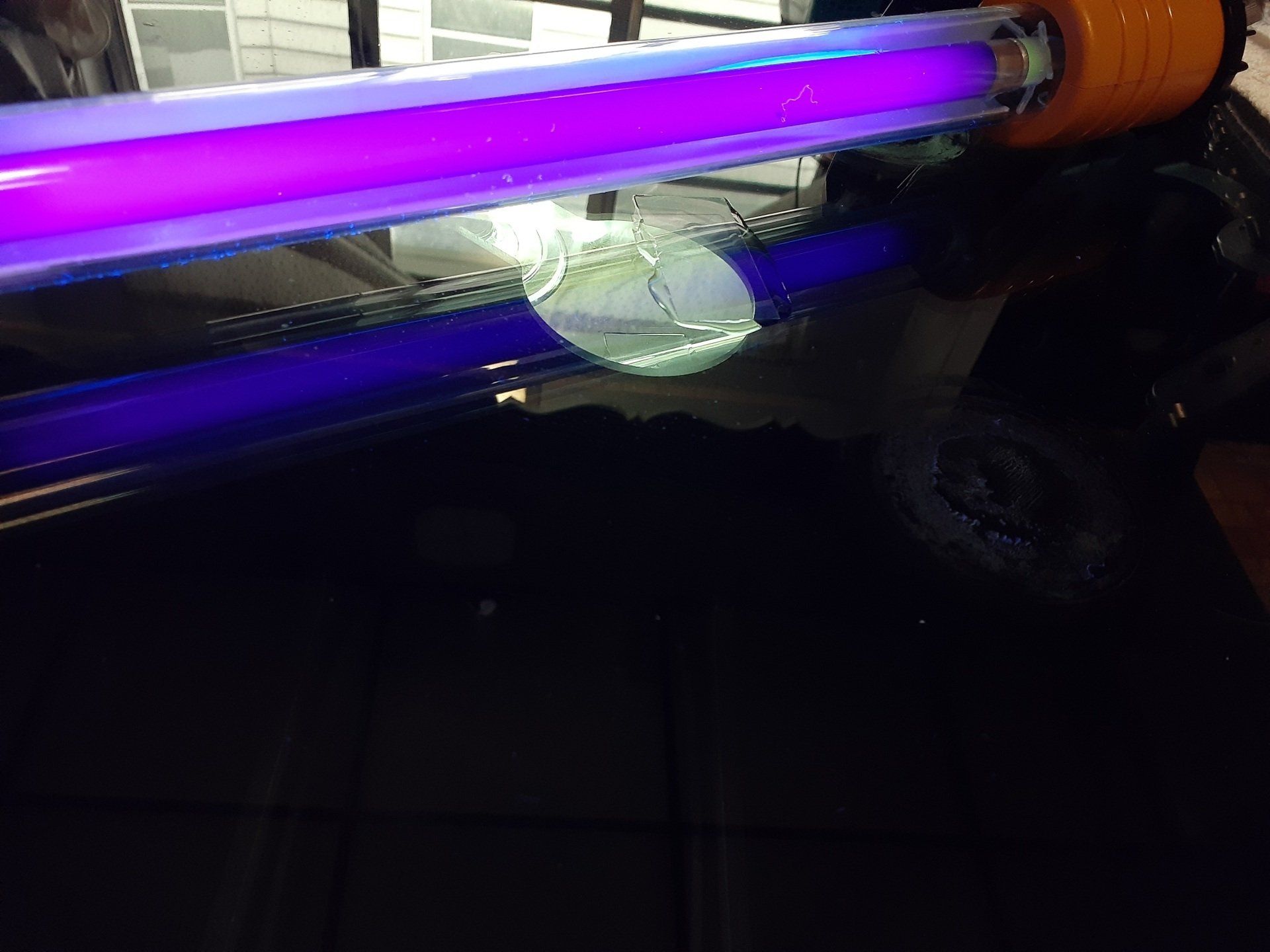 A purple light bulb is sitting on a table in a dark room.