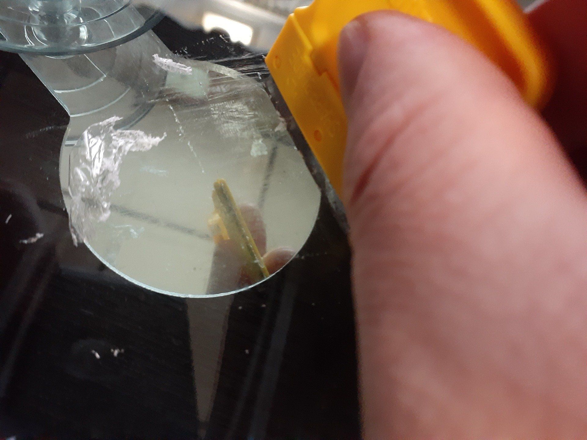 A person is cleaning a broken glass with a yellow sponge