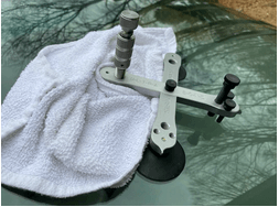 A tool is sitting on top of a towel on a car windshield.